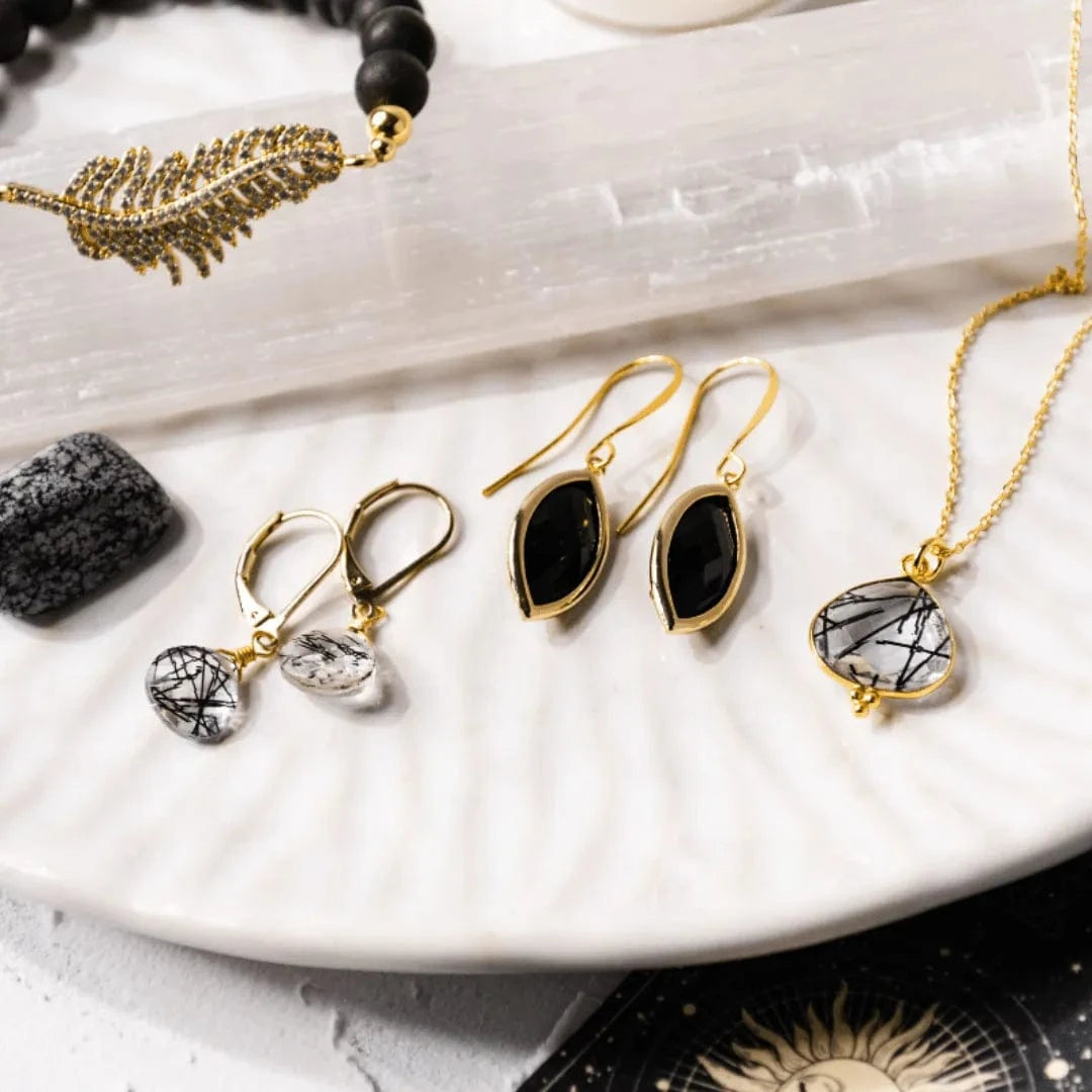 Jewelry set including earrings and necklaces on a white surface with a stone and bracelet.