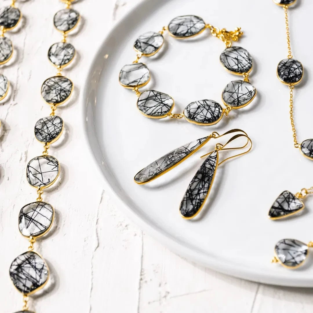 Jewelry set with black and gold necklaces and earrings on a white surface