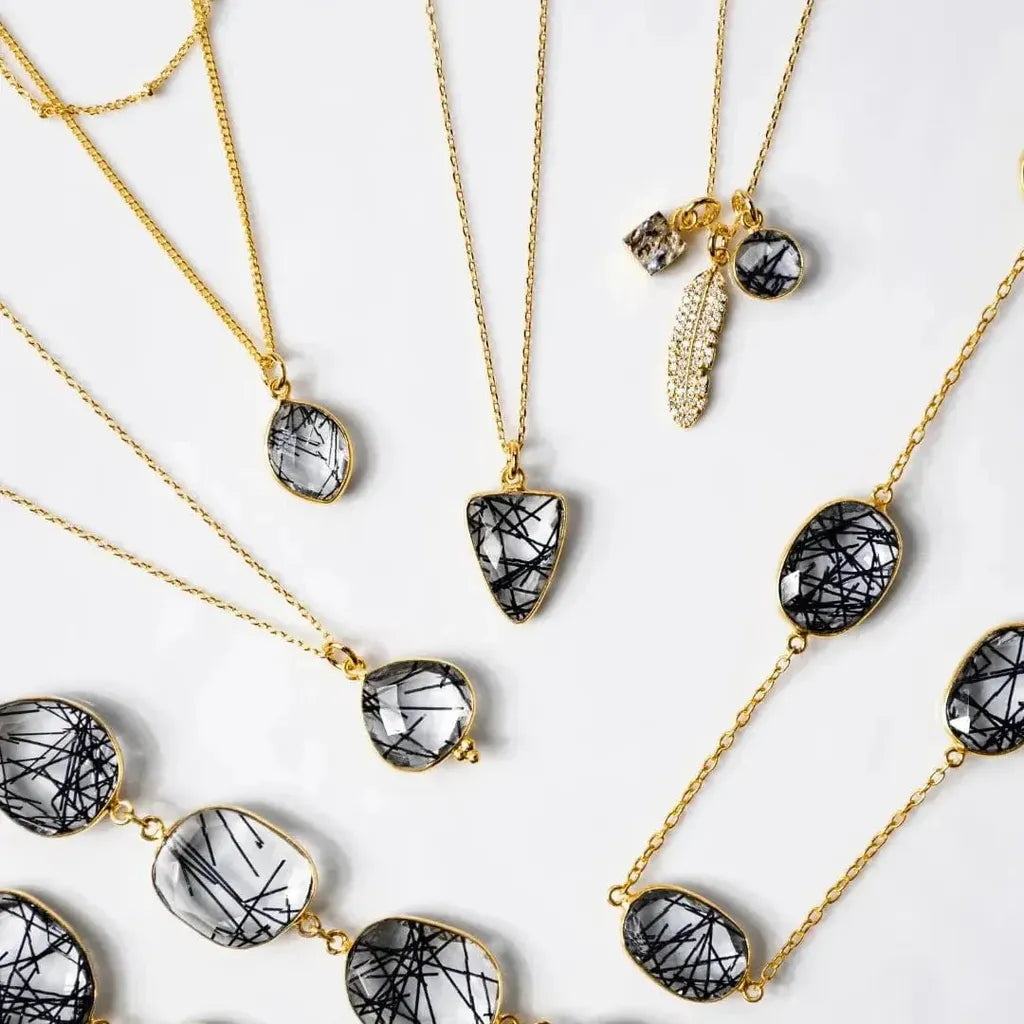Gold necklaces with black and white stone pendants on a light background