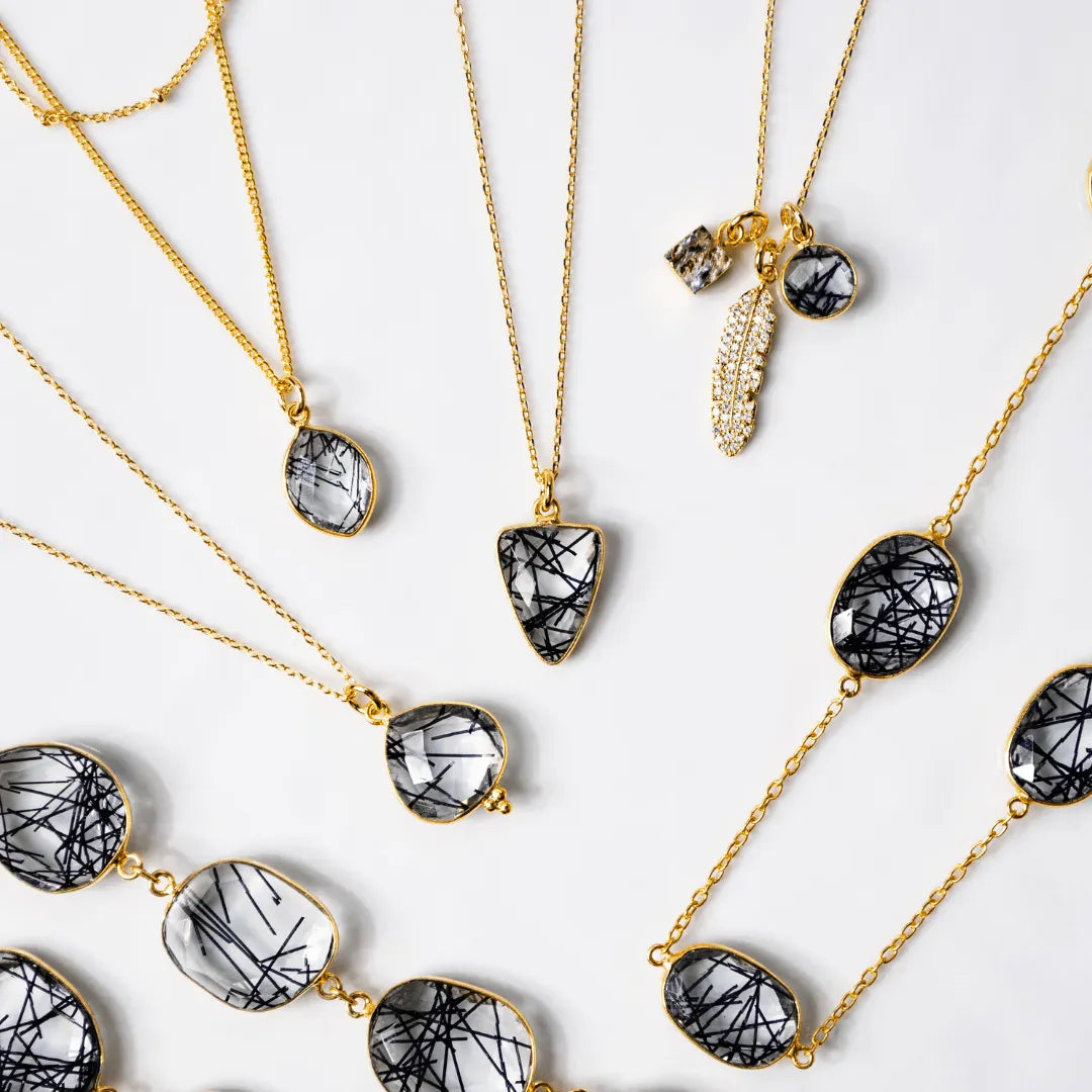Gold necklaces with black and white stone pendants on a light background