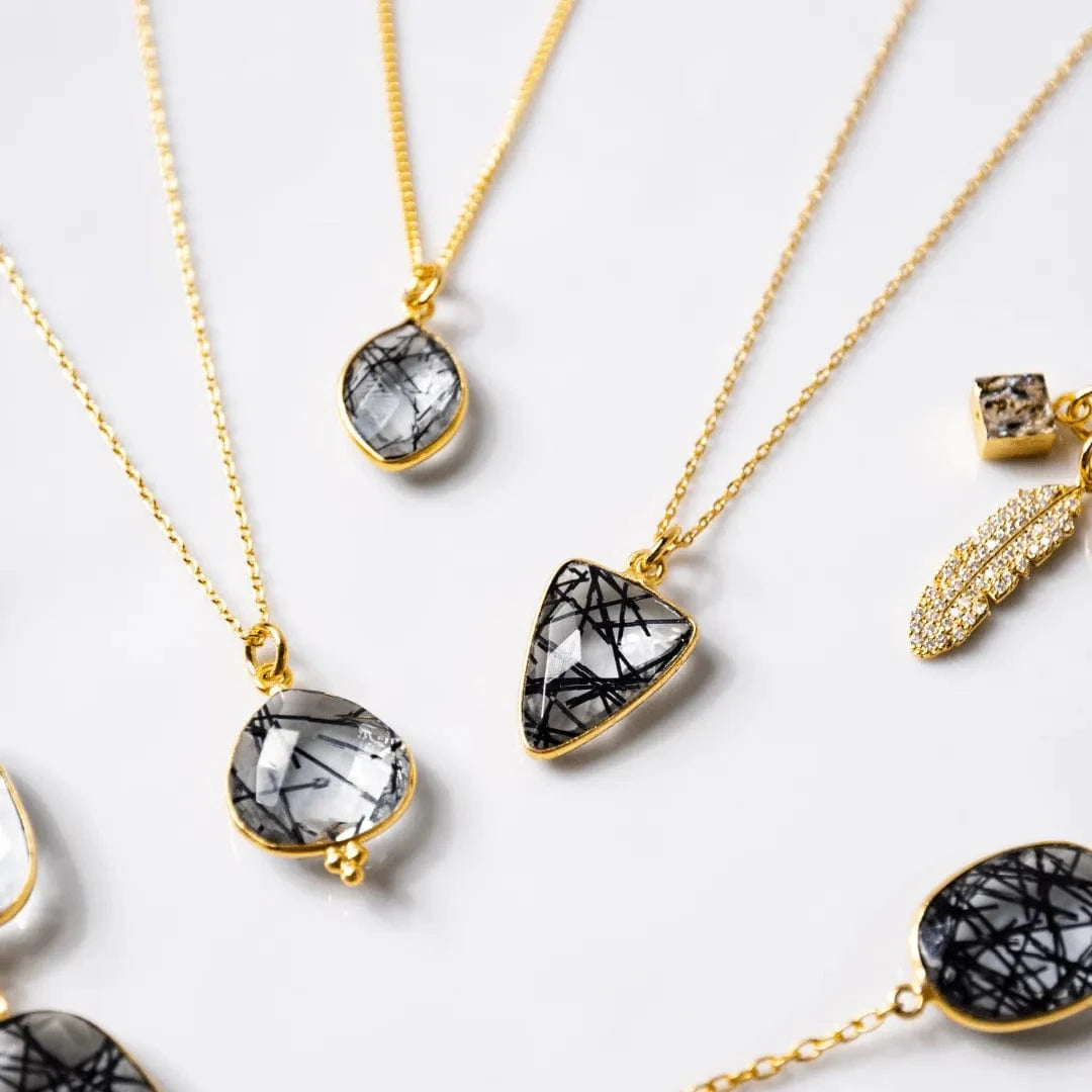 Gold necklaces with black and white stone pendants on a light background