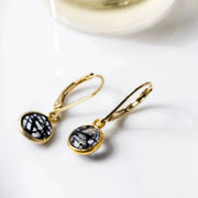 Gold earrings with black gemstones on a white background