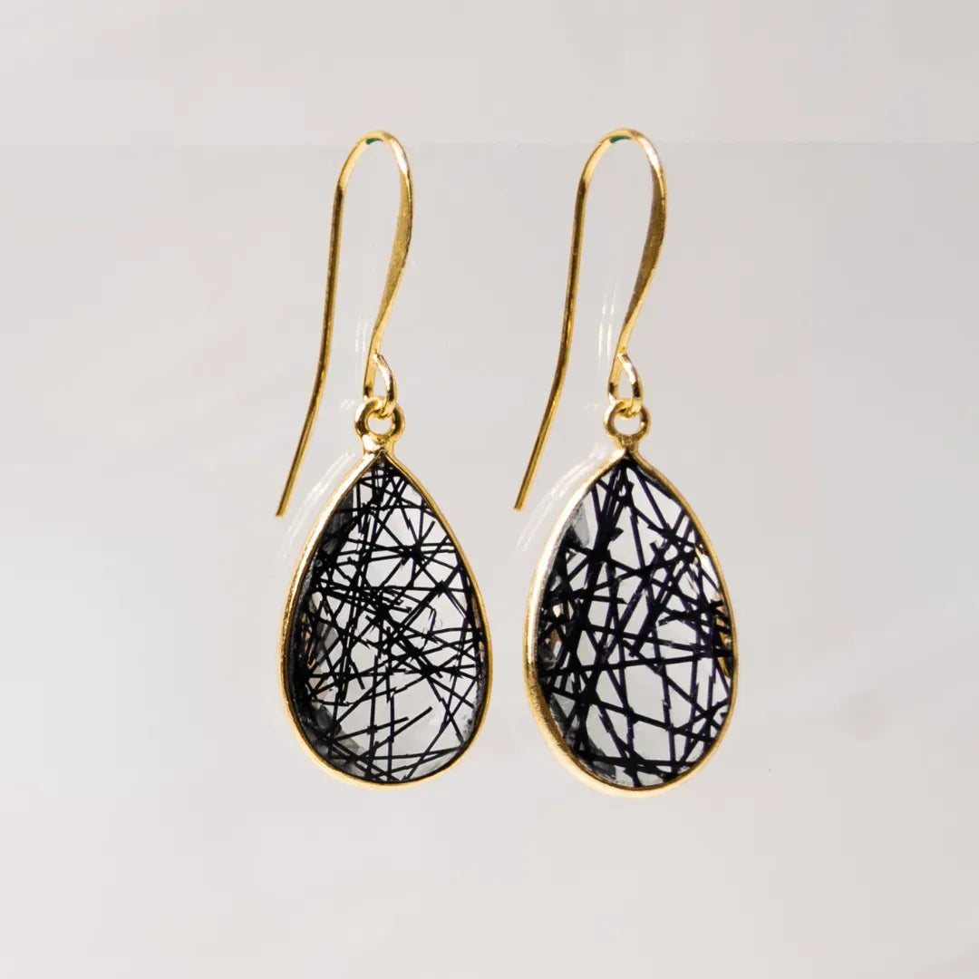 Teardrop-shaped earrings with black string design on gold hooks against a light gray background