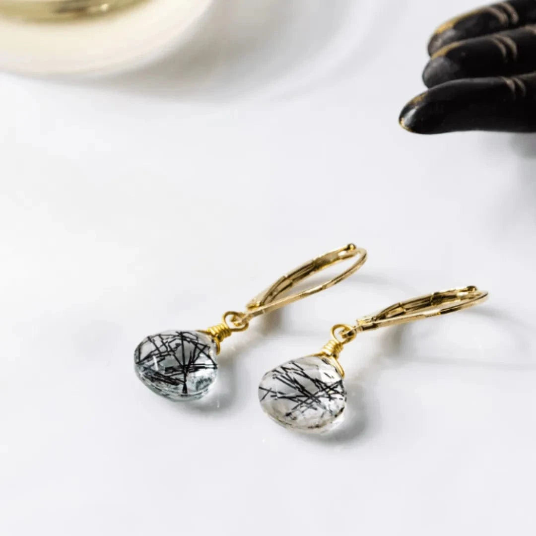 Gold earrings with clear teardrop-shaped stones on a white surface.