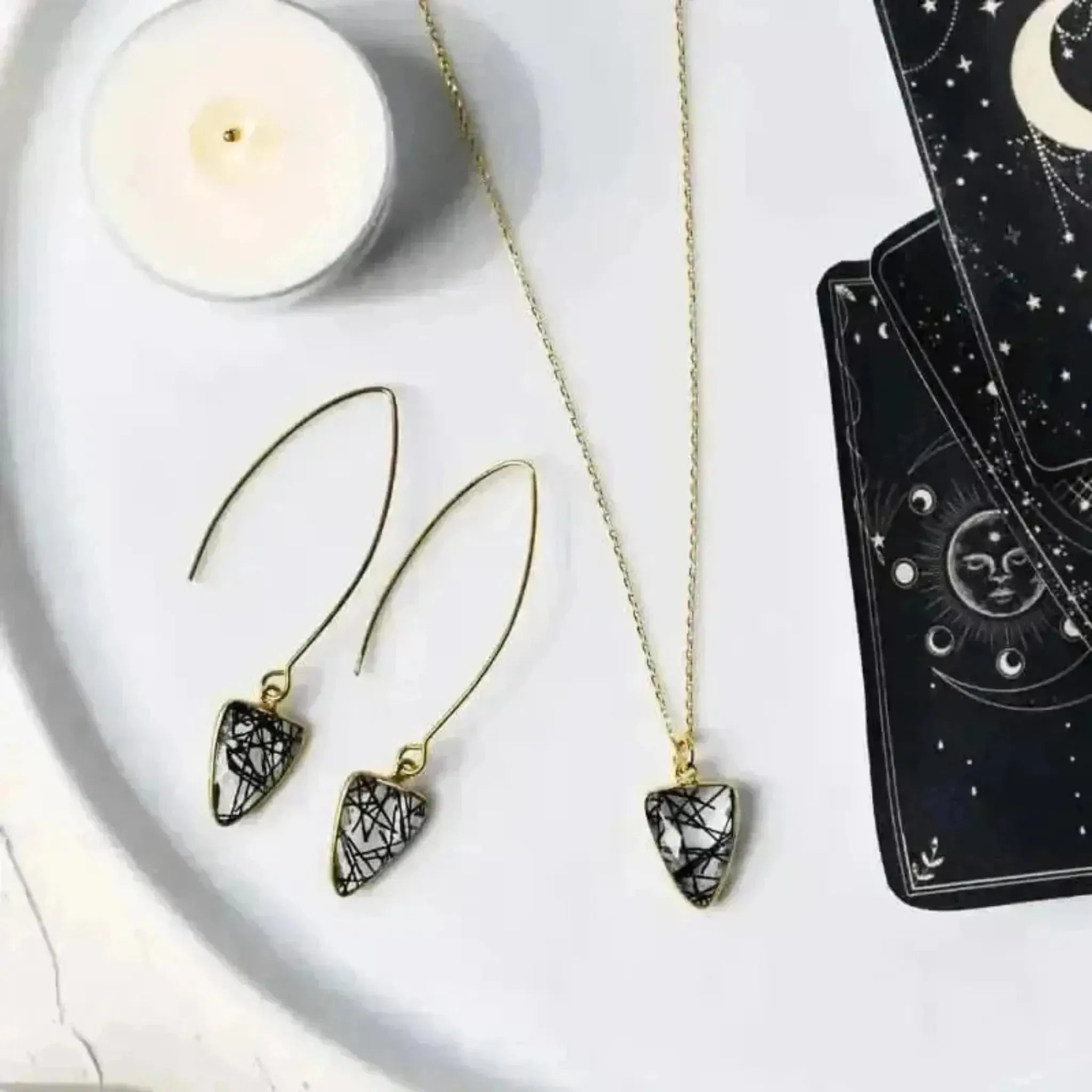 rutilated quartz inversed triangle shaped necklace and earrings with candle and tarot cards
