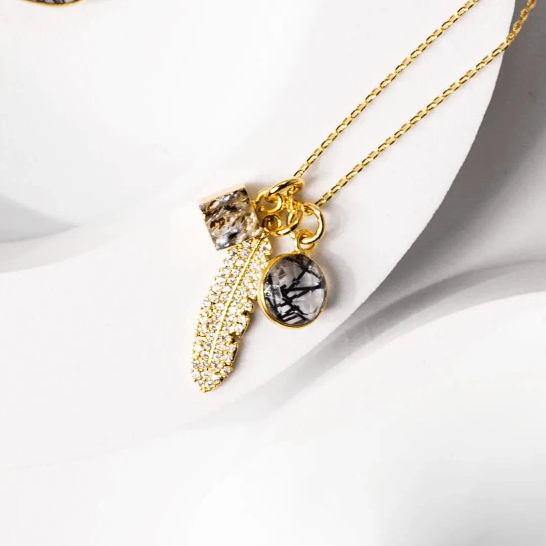 Gold necklace with various charms on a white surface