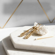 Gold earrings on a marble surface with a geometric background
