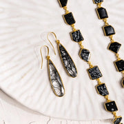 Black and gold jewelry set on a white shell background