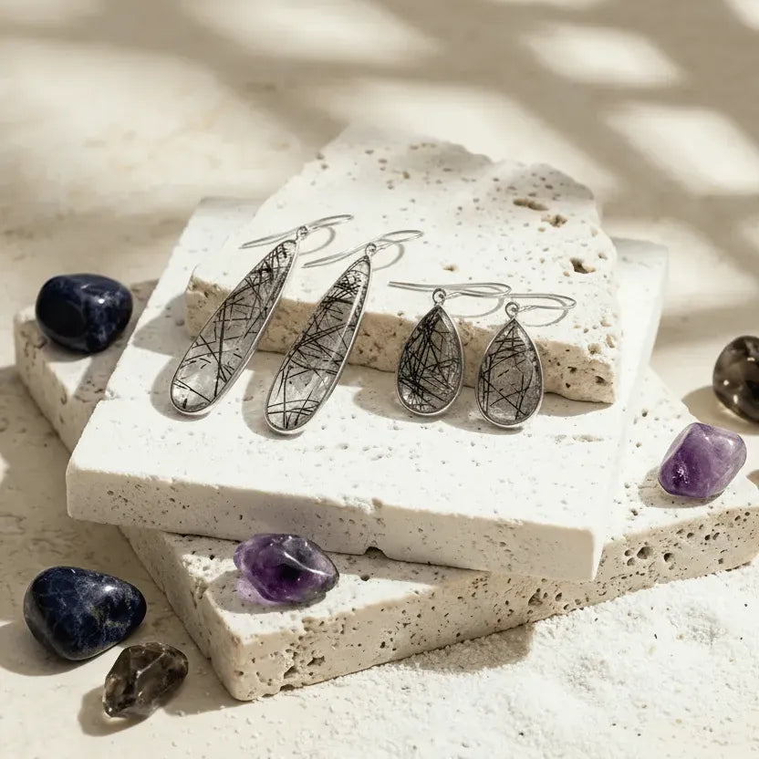 Silver teardrop earrings on a textured stone surface with stones around