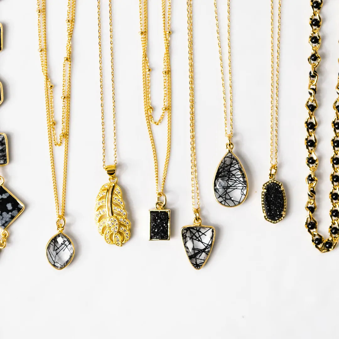 Collection of gold and black necklaces on a white background