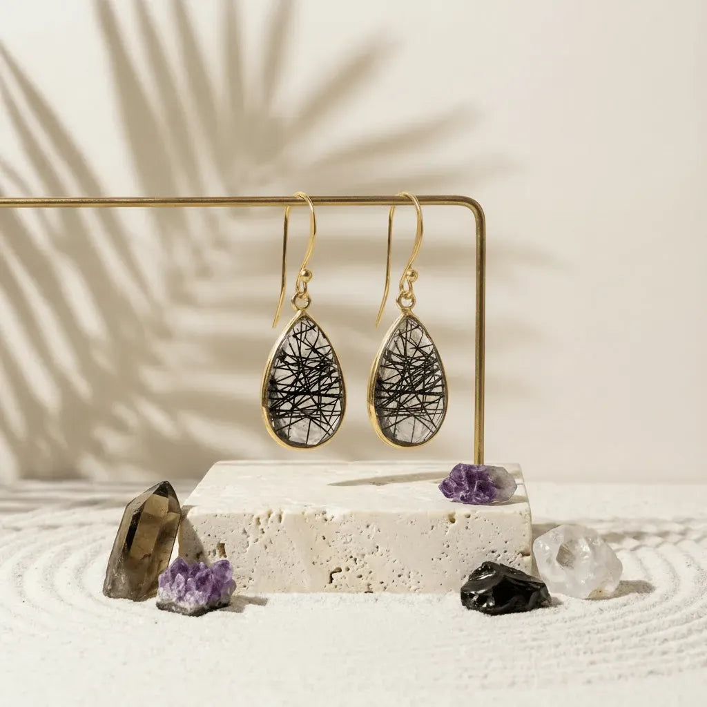 Gold earrings with black and white design on a beige stand with crystals