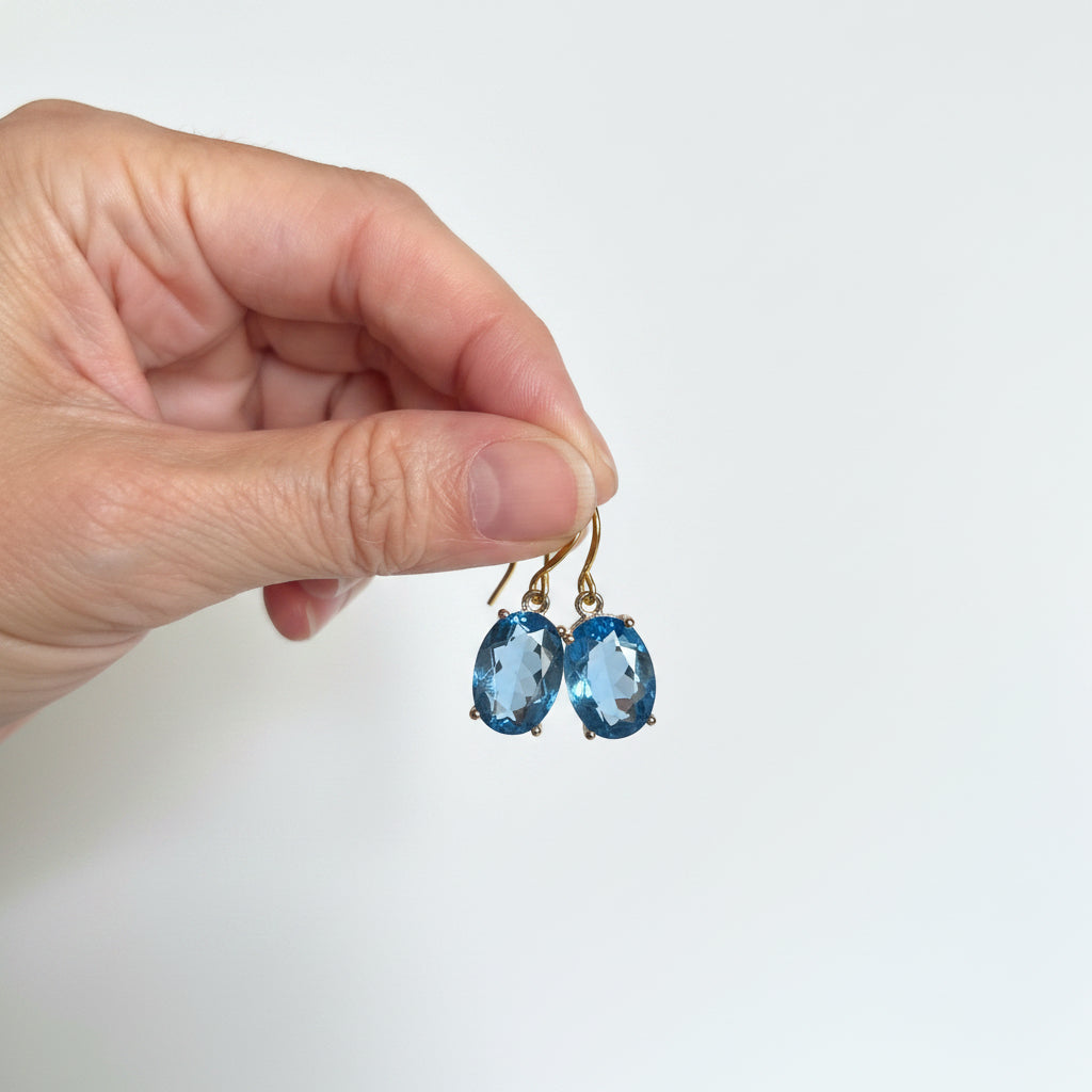 Hand holding gold sapphire blue ombré glass drop earrings, shown for scale