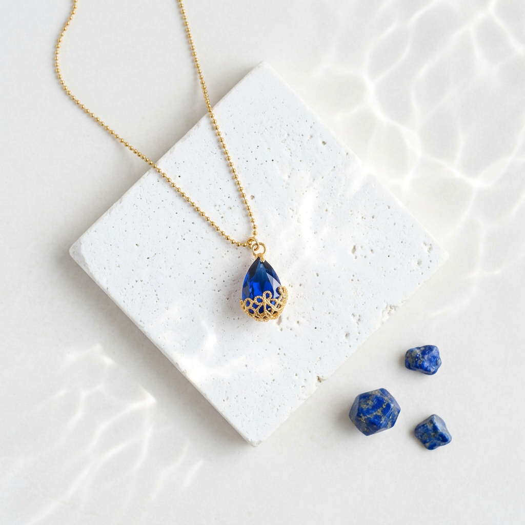 Small gold Flower-Cap necklace with vivid sapphire blue glass drop