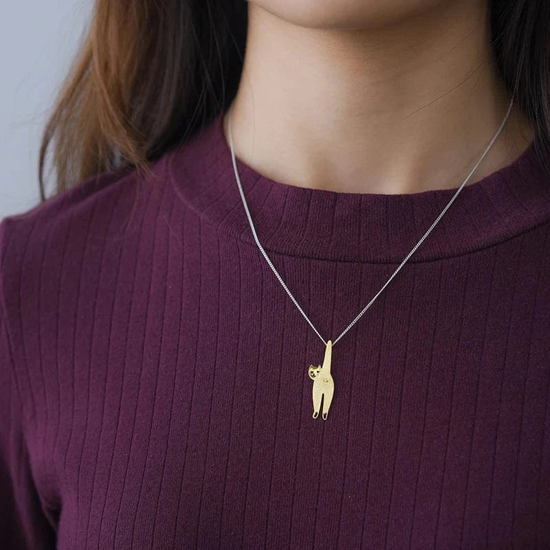 Person wearing a gold cat pendant necklace on a plain background