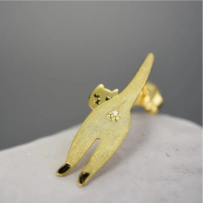 Gold cat-shaped earring on a gray background