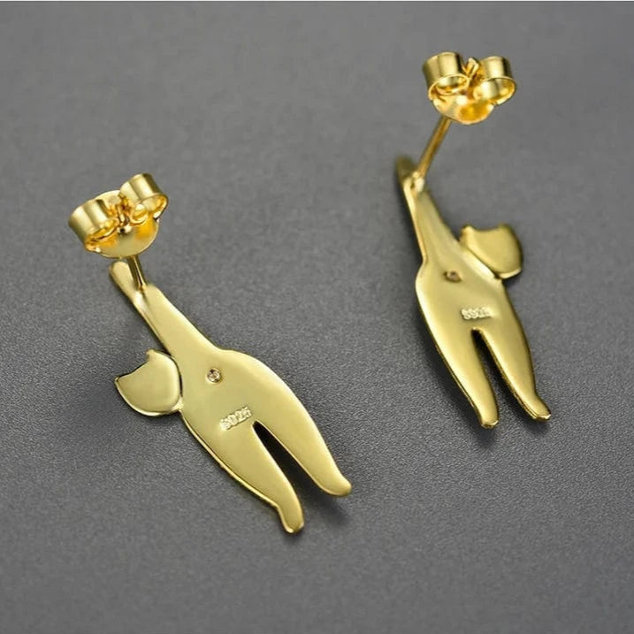 Gold cat-shaped earrings on a gray background