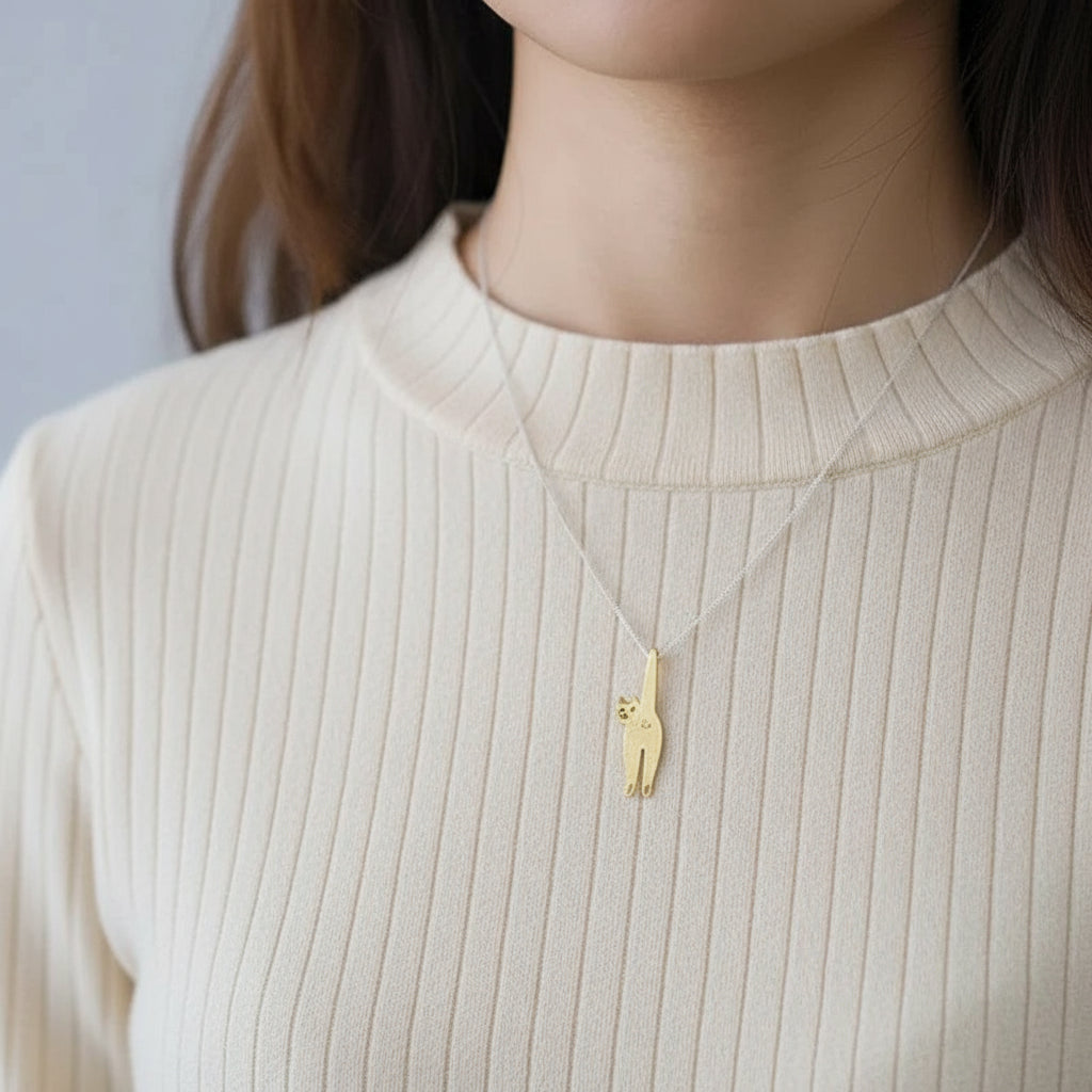 Person wearing a gold cat pendant necklace on a plain background
