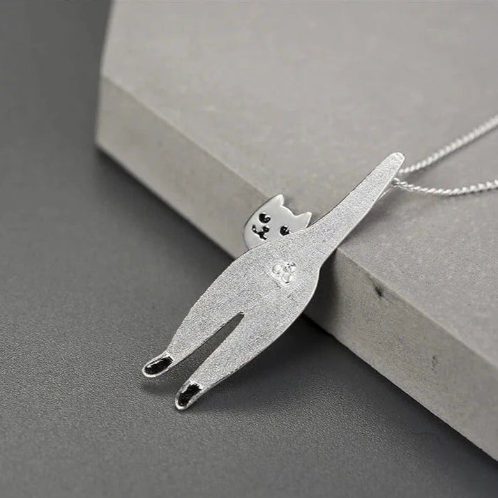 Silver cat-shaped pendant on a chain against a gray background