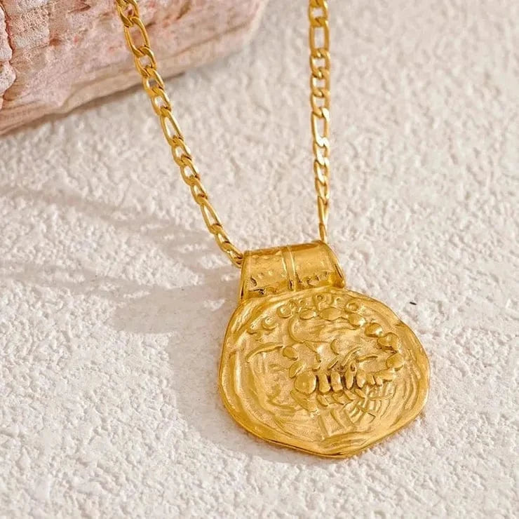 Gold necklace with a coin pendant on a textured surface