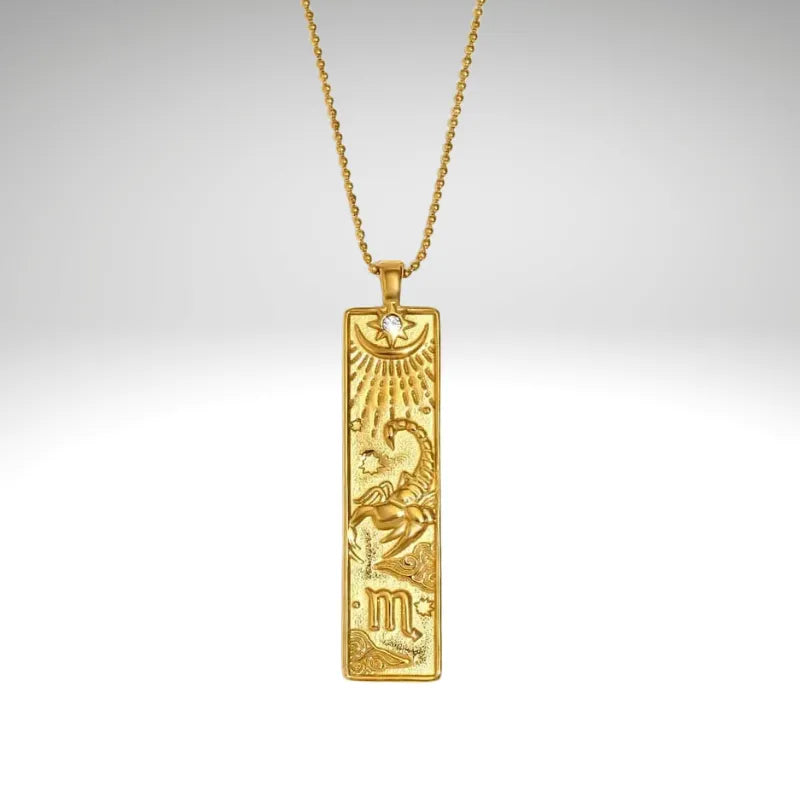 Gold pendant with zodiac symbol on a chain against a gray background