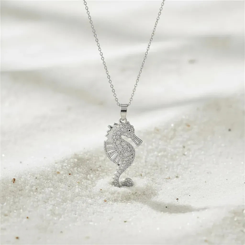 Silver seahorse necklace on a sandy background
