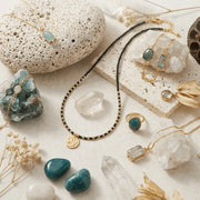 Jewelry set with necklaces, rings, and stones on a textured surface