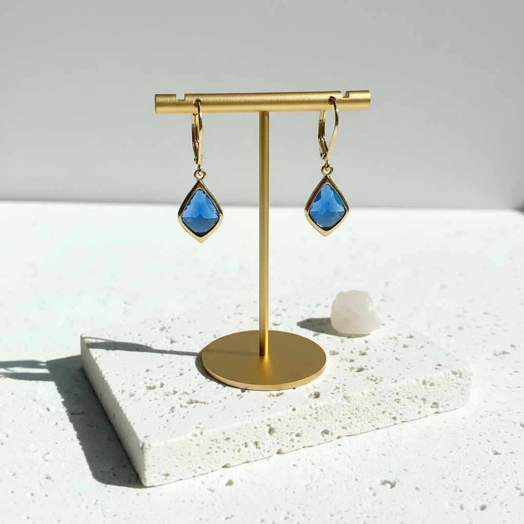 Selene gold drop earrings hanging on a jewellery stand