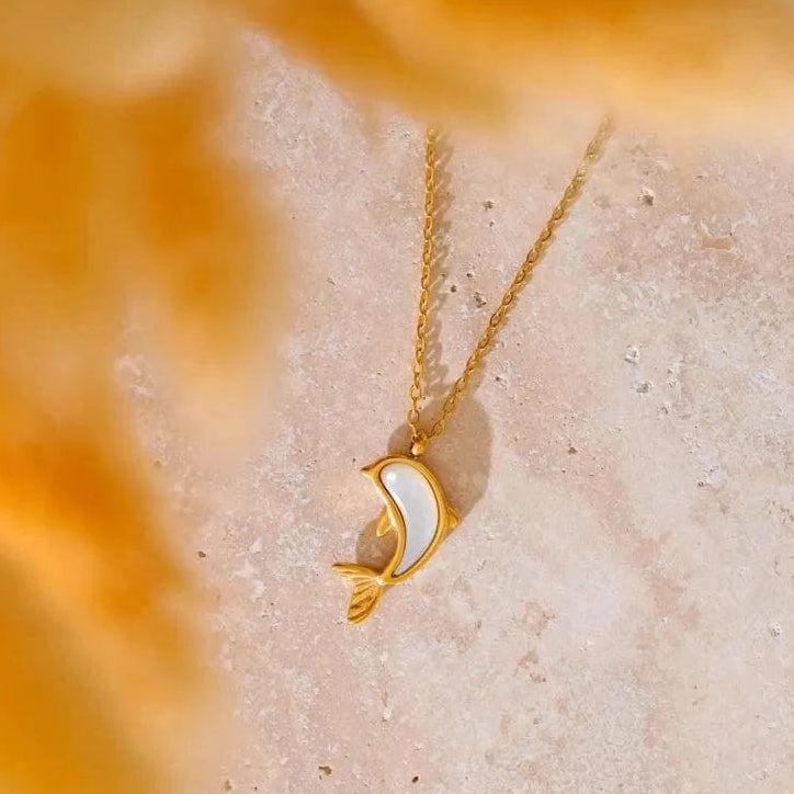 Gold necklace with a moon design on a textured beige surface
