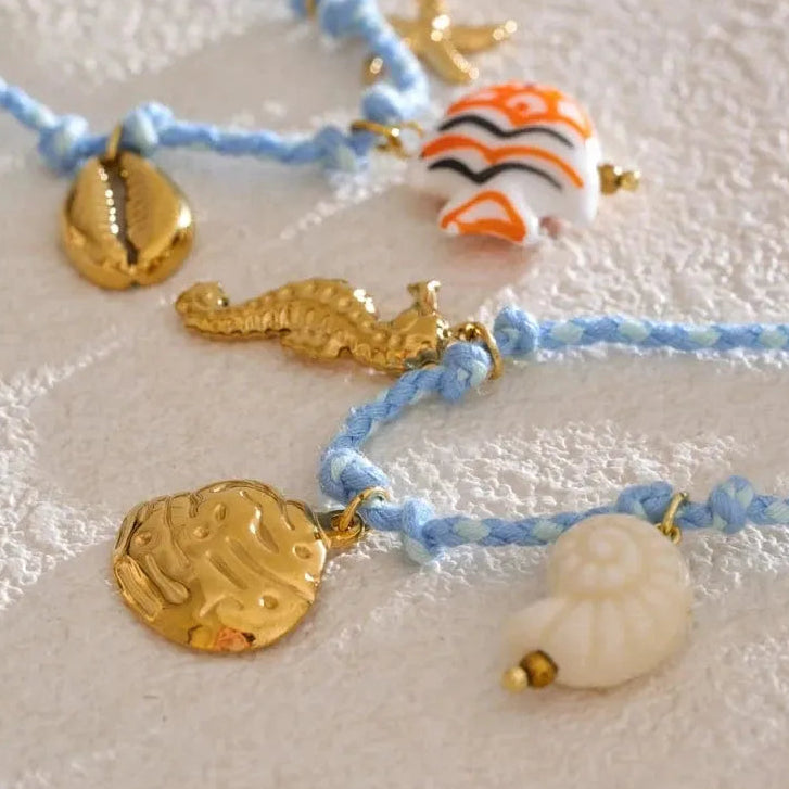 Necklace with gold and sea-themed charms on a textured surface