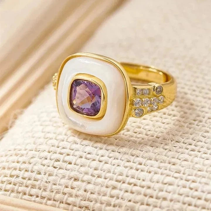 Gold ring with a purple gemstone on a beige fabric background, mystic soul jewelry