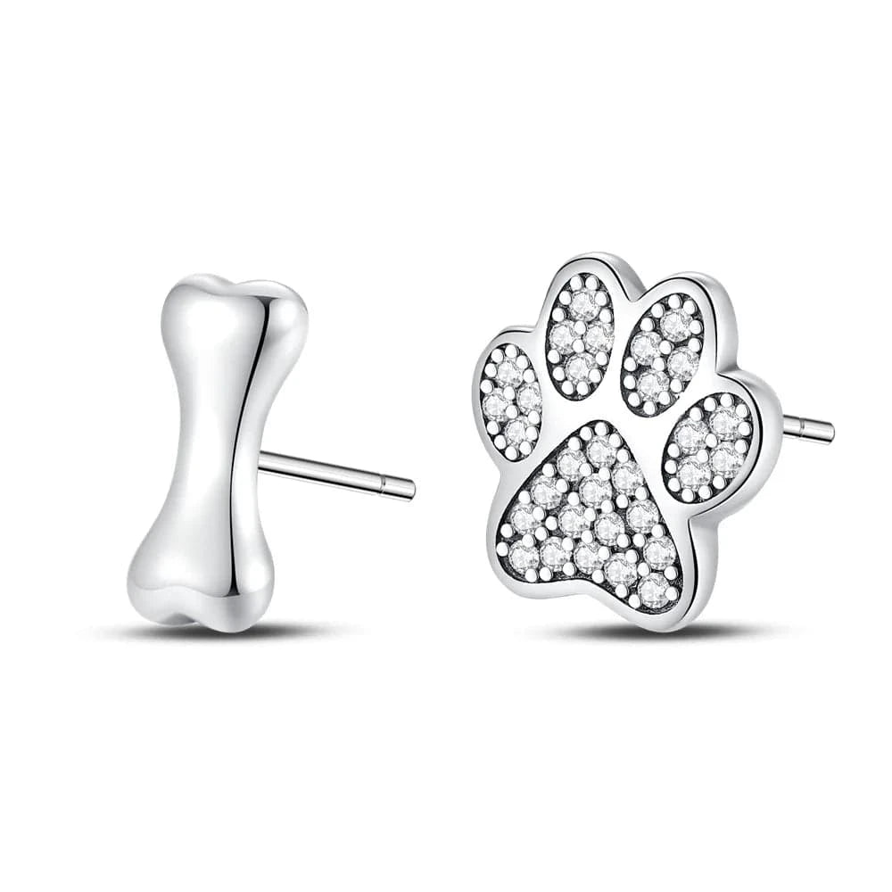 Silver paw print and bone-shaped earrings on a white background
