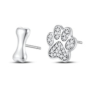 Silver paw print and bone-shaped earrings on a white background