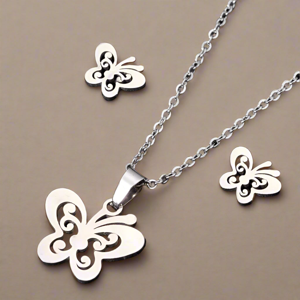 Butterfly necklace and earrings set on a black glittery background