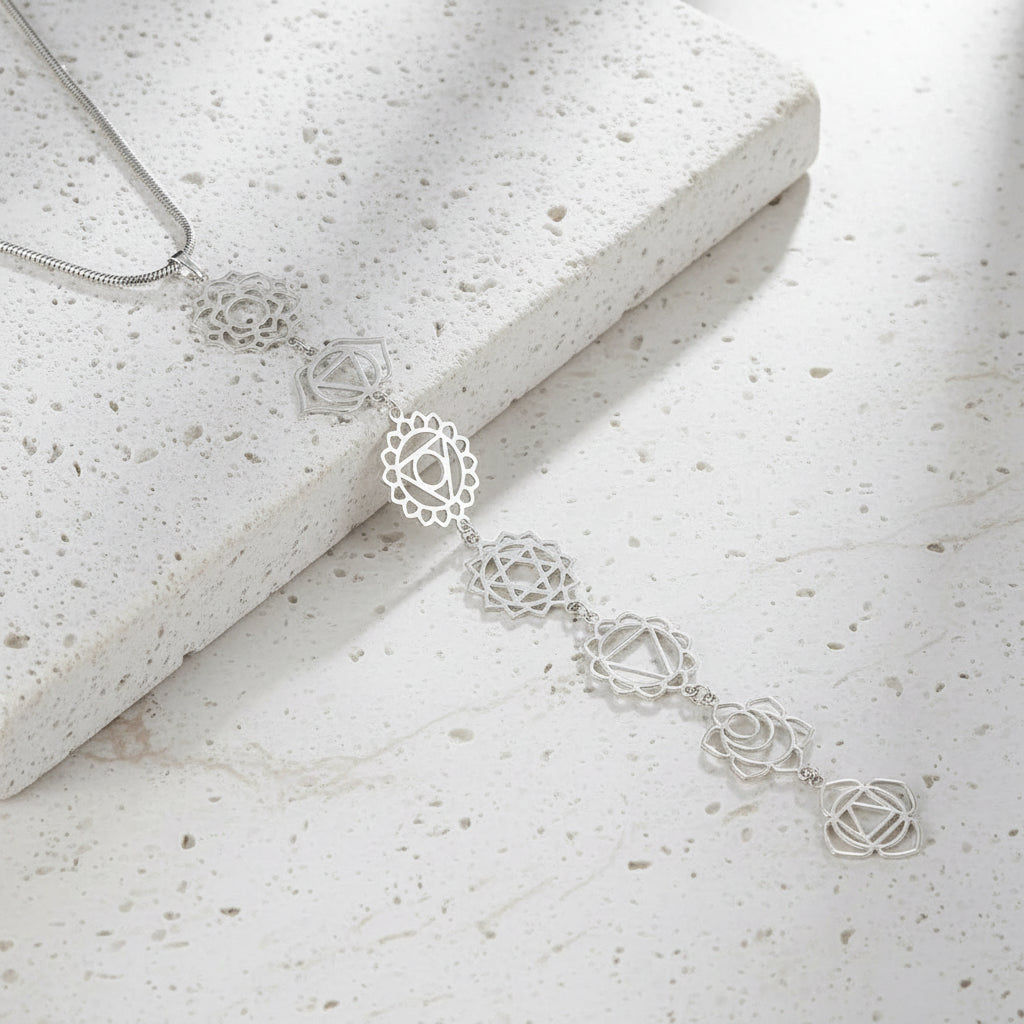 Silver chakra necklace with intricate design on a white background