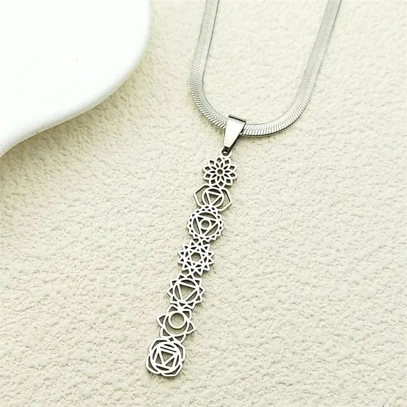 Silver necklace with a detailed pendant on a textured beige surface