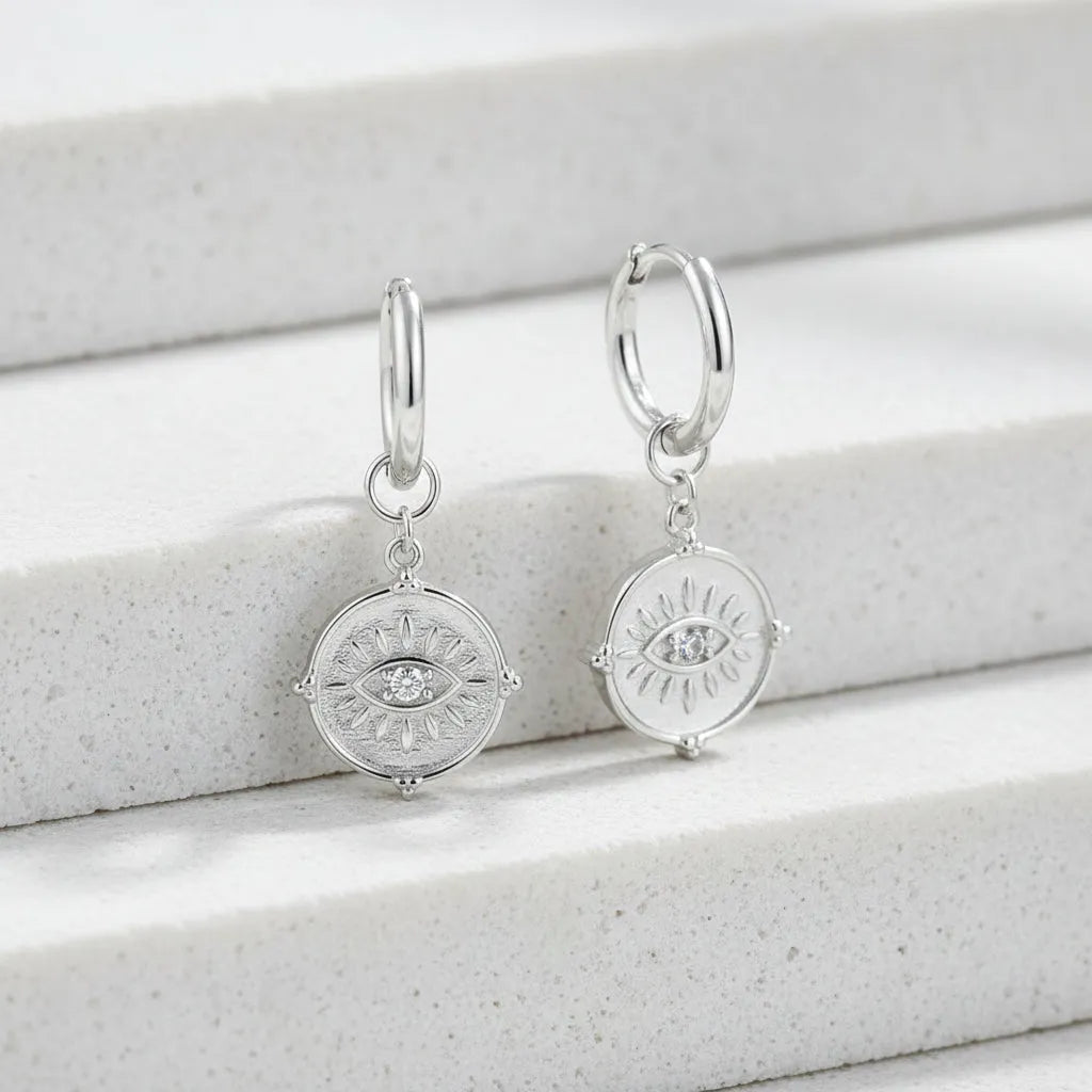 Pair of silver earrings with circular designs on a white background 