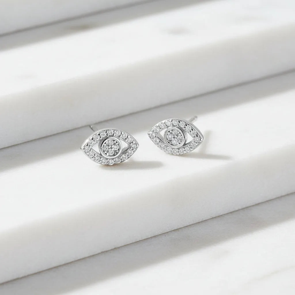 Silver eye-shaped earrings with clear stones on a white background
