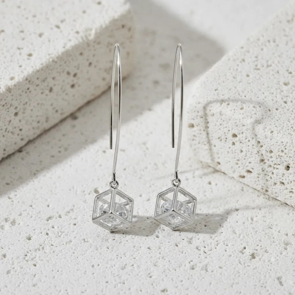 Silver geometric earrings on a textured stone surface