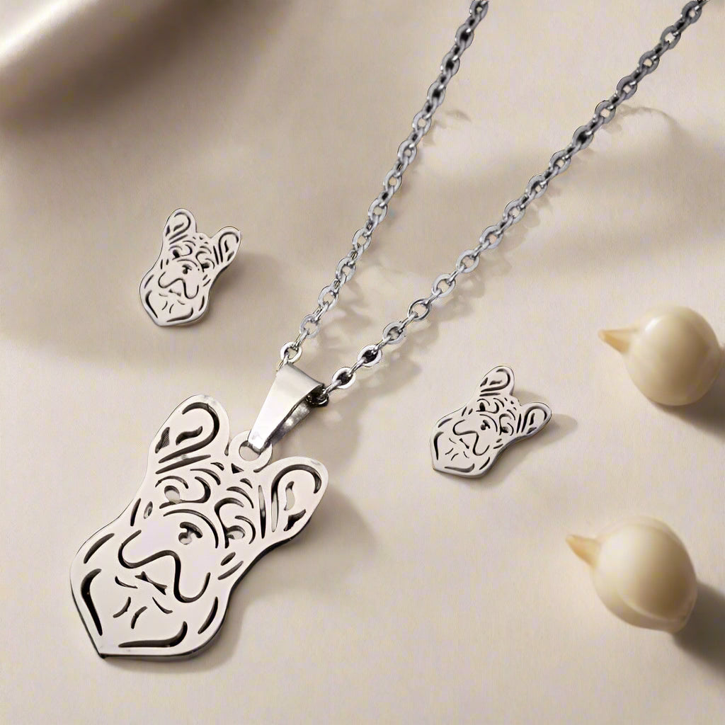 Silver lion head necklace and earrings on a black background