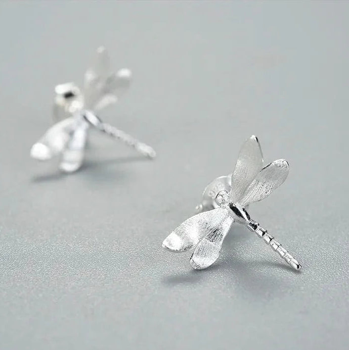 Silver dragonfly earrings on a gray background