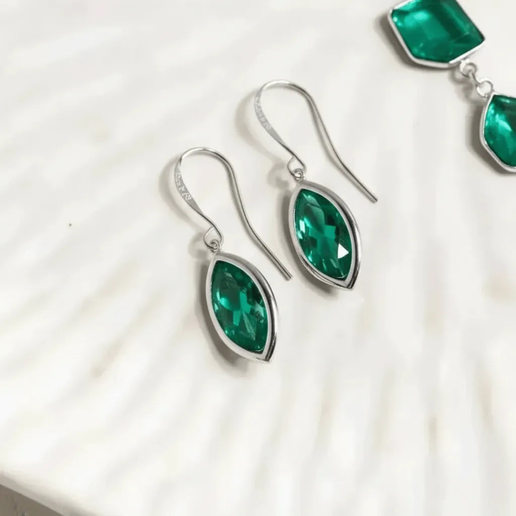 Green teardrop earrings with silver hooks on a white background