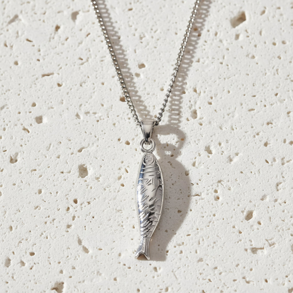 Silver fish pendant on a chain against a white background