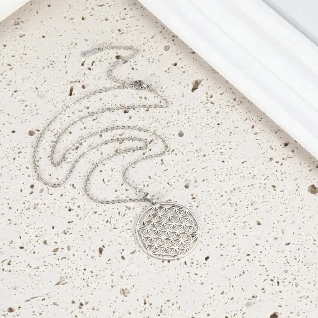 Silver necklace with a geometric pendant on a teal surface