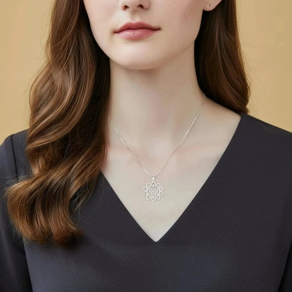 Woman wearing a delicate silver necklace with a floral pendant against a beige background