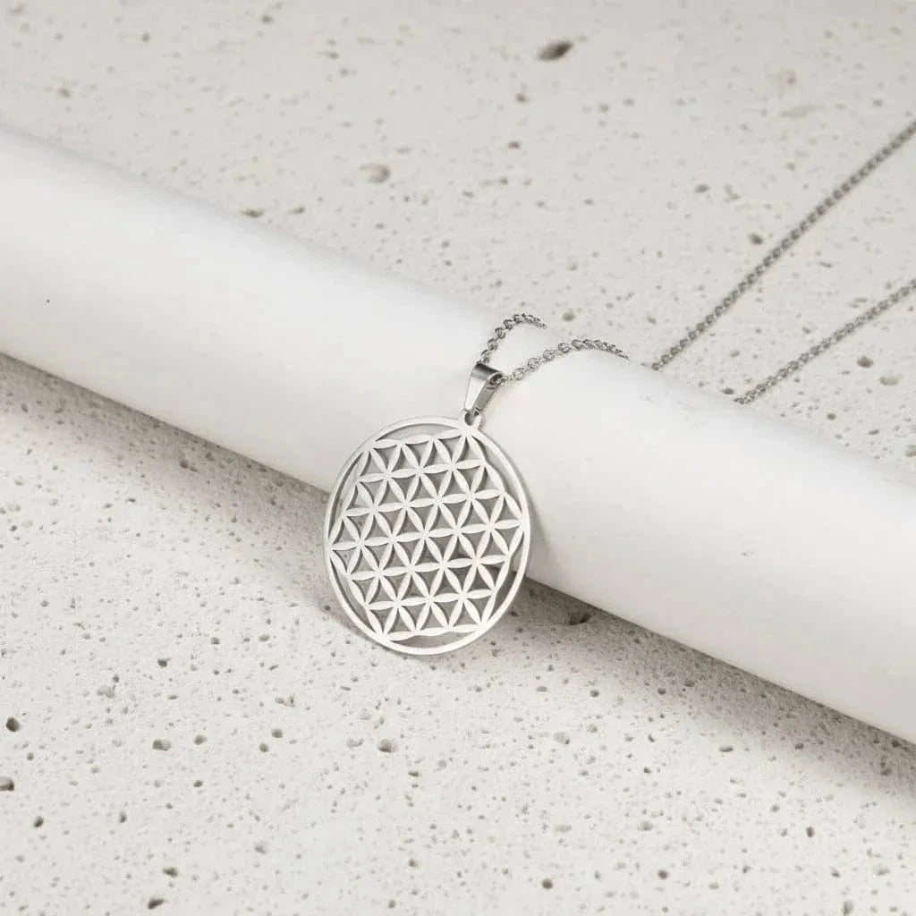 Silver geometric pendant necklace on a white cylindrical object with a white background