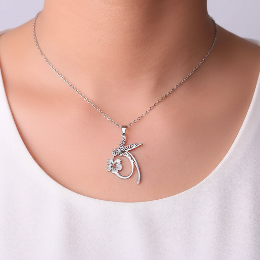 Silver necklace with a unique pendant worn by a person against a neutral background