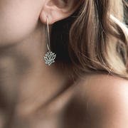 Close-up of a person wearing a silver lotus flower earring.