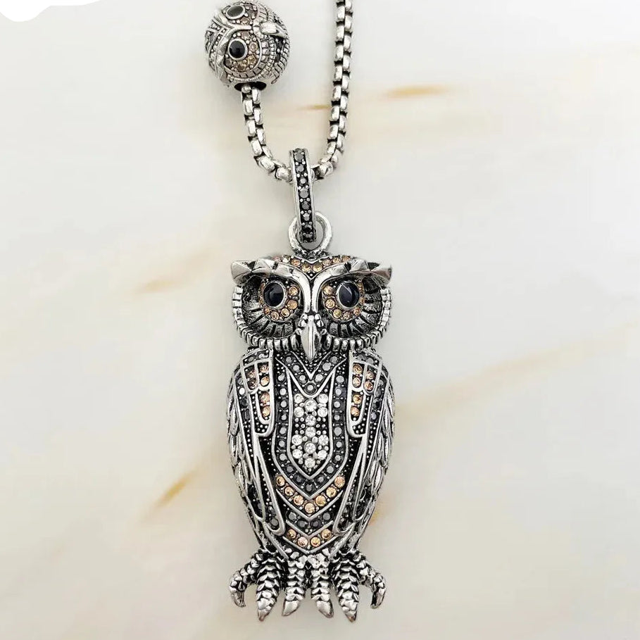 Silver owl pendant necklace on a light background