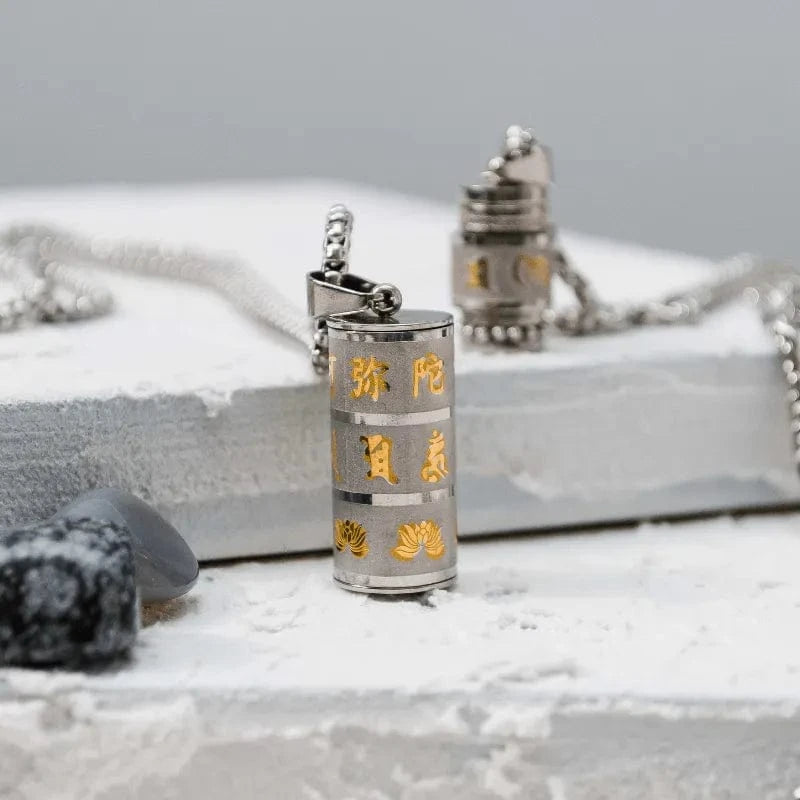 Silver cylindrical pendant with gold text and designs on a gray surface