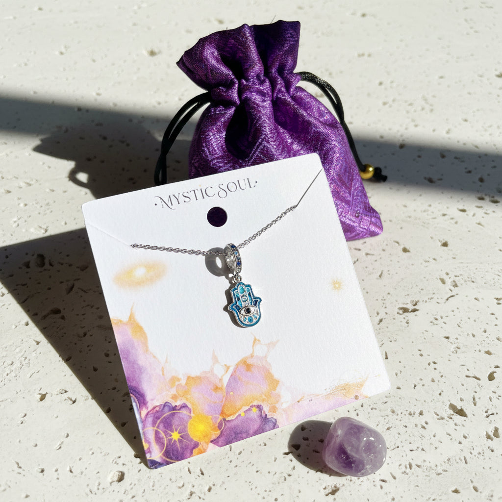 Sterling silver hamsa hand pendant with a blue centre displayed on a Mystic Soul Jewelry card